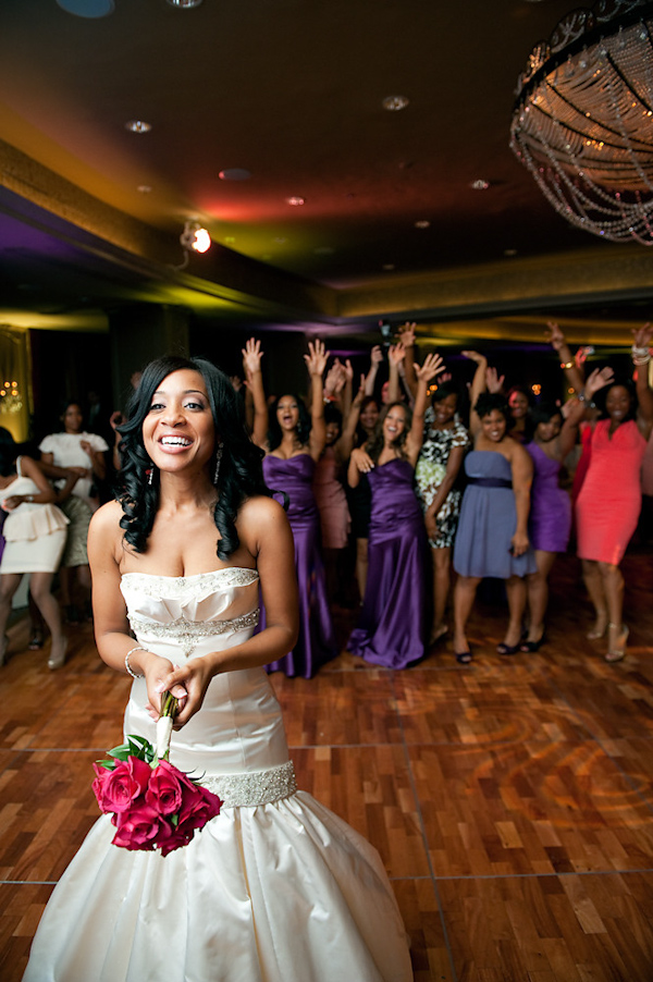 bride in champagne mermaid style dress holding dark pink bouquet with her back to the single ladies waiting to catch the bouquet - photo by Houston based wedding photographer Adam Nyholt